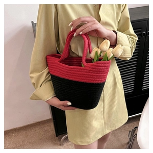 Detail of red and black woven straw bucket bag with floral tulips on model side view