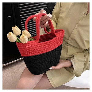 Detail of red and black woven straw tote bag with dense stitching and tulip floral accent