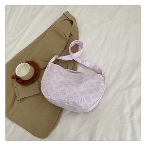 Détail du sac à bandoulière en demi-lune tissé violet clair sur fond de tissu minimaliste