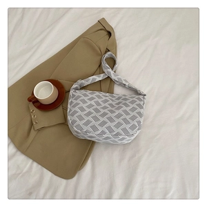 Détail du sac dumpling en toile à motif géométrique gris avec large bandoulière assortie
