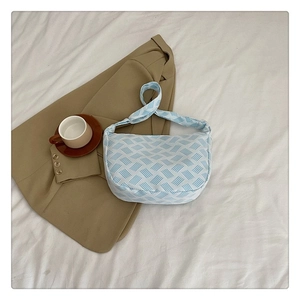 Détail du sac croissant à rayures bleu clair sur un blazer avec une tasse de café