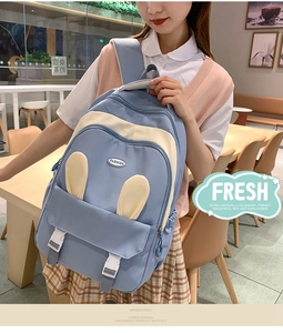 Blue and yellow backpack with rabbit ears and buckle flap detail in a cafe setting
