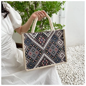 Dettaglio di motivi geometrici intrecciati e manici in corda su una borsa tote in tela
