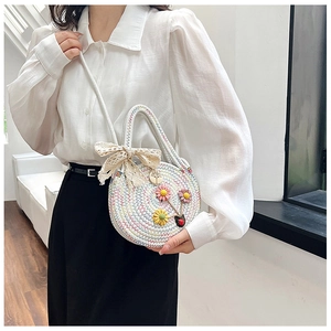 Détail du sac de plage rond tissé main avec accents floraux 3D et nœud en dentelle délicat