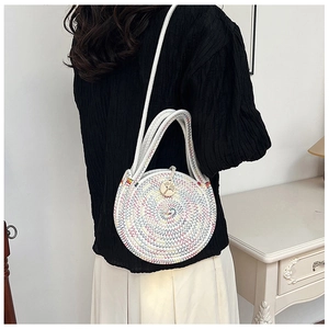 Détail d'un sac rond en paille tissée avec cordes de coton colorées et fermeture bouton bois