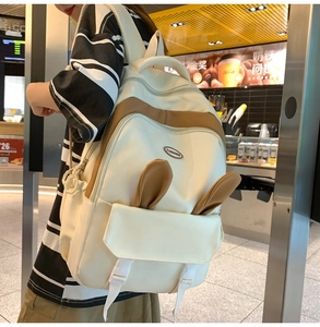 Detail of minimalist cream backpack featuring brown accents and cute bunny ear decor