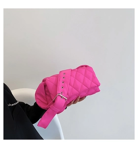 Détail du sac matelassé rose vif en nylon avec boucle argentée porté sur un tailleur noir