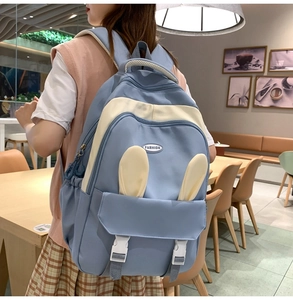Detail view of light blue school backpack featuring cute bunny ears on outdoor model