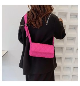 Détail du sac bandoulière fuchsia en nylon matelassé avec nœud décoratif sur la sangle