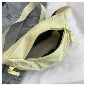Close-up of nylon crossbody bag interior with black mesh pocket and zipper puller detail