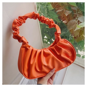 Detail shot of the orange pleated cloud bag texture and ruched handle in matte PU leather