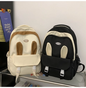 Detail of two cartoon rabbit ear backpacks with dual buckles on a display shelf