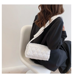 Détail latéral d'un sac bandoulière blanc matelassé avec une large sangle réglable