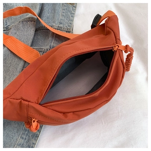 Close-up of vibrant orange nylon chest bag showing spacious black interior and zipper