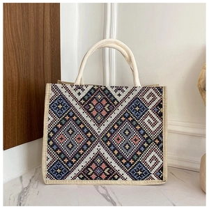 Dettaglio della borsa tote geometrica intrecciata con robusti manici in corda di cotone