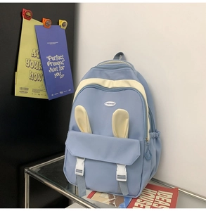 Detail of light blue backpack featuring cute rabbit ears and fashion metal logo badge