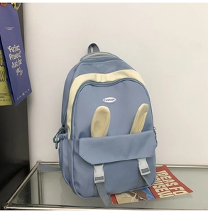 Detail of light blue backpack featuring cute white rabbit ear decor and round logo
