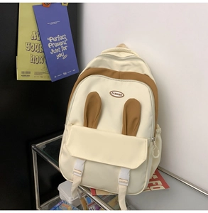 Close-up of beige school backpack with cute rabbit ears and functional front buckle pocket