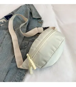Detail of cream nylon moon bag with thick strap and woven rope zipper pull decoration