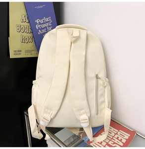 Detailed back view of a cream nylon backpack featuring padded straps and an anti-theft pocket