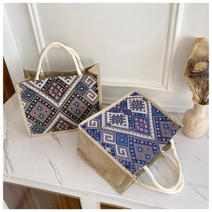 Dettaglio di borsa tote boho con ricamo geometrico e manici in corda intrecciata su marmo