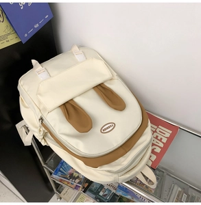 Detail of cute rabbit ear design on a cream and brown canvas backpack with fashion logo