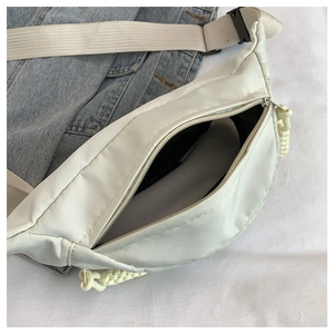 Close-up of minimalist cream nylon waist bag with yellow zip pulls on denim background