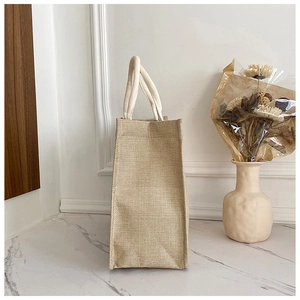 Dettaglio di una piccola borsa in juta con manici in corda bianca su piano in marmo