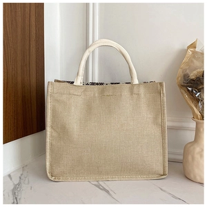 Dettaglio di una borsa tote in juta beige con trama intrecciata e manici crema