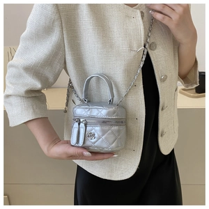 Détail du mini sac seau argenté matelassé avec finition métallisée et fleur en métal