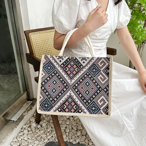 Borsa tote in tela con motivo geometrico etnico e manici intrecciati in posa lifestyle