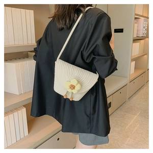 Detalle del bolso tipo cubo de punto crema con un adorable colgante de flor de margarita