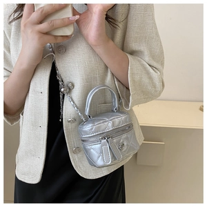 Détail d'un mini sac seau matelassé argenté avec finition métal et breloque fleur