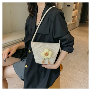 Detalle de bolso bandolera tejido blanco con flores 3D amarillas y colgante naranja