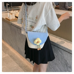 Detalle del bolso tipo cubo tejido con un girasol en 3D y borlas verdes decorativas