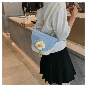 Detalle del bolso bandolera tejido con una flor de punto amarilla y un pompón
