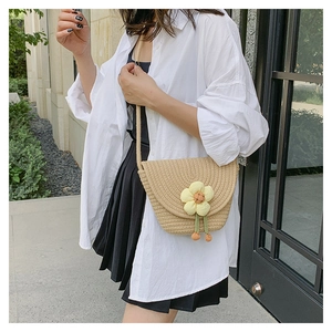Vista detallada del bolso de paja trenzada beige con flor y correa delgada