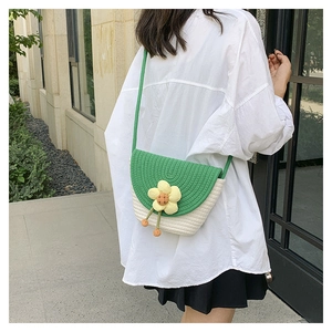 Detalle de bolso saco tejido a mano con solapa verde y detalle de flor amarilla en 3D