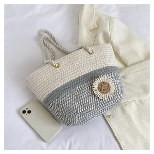 Close-up of woven tote bag with a white daisy flower detail and sturdy cotton rope handles
