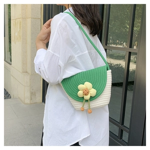 Detalle del bolso bandolera tejido a mano con solapa verde y flor amarilla tejida
