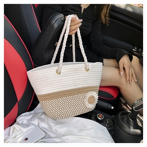 Detailed shot of a woven tote bag featuring a white daisy accent and cotton rope handles