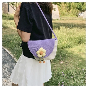 Detalle del bolso de cubo tejido en morado y blanco con flor amarilla y correa de cuerda