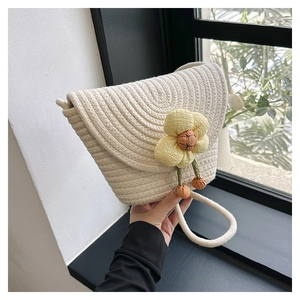 Detalle de bolso tipo cubo de punto crema con flor amarilla y correa de cuerda