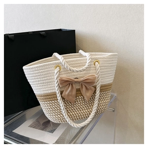 Close-up of woven tote bag with beige velvet bow detail and thick cotton rope handle