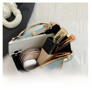 Internal view of light blue woven clutch bag showing capacity for phone and cosmetics
