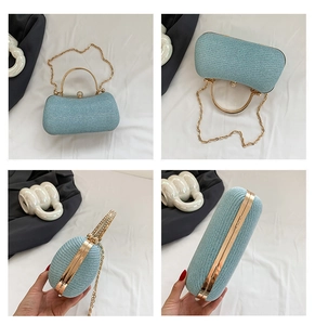 Close-up of light blue textured evening bag with crystal clasp and golden ring handle