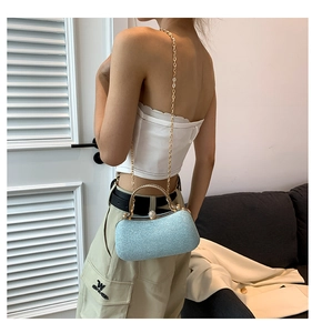 Detail of light blue glitter clutch bag with golden chain and metal handle in lifestyle setting