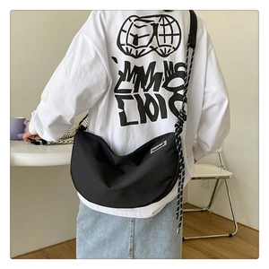Detail of black nylon crescent bag with woven rope strap and silver logo plaque