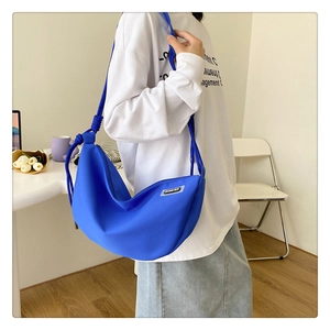 Detail of royal blue nylon crescent bag with adjustable shoulder strap and side label