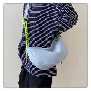 Blue nylon crossbody dumpling bag with lime green rope strap worn by a model